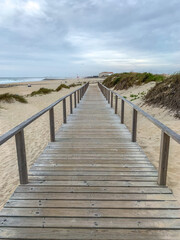 Boardwalk crossing the sand dunes in Costa Nova, Portugal with the ocean on the background