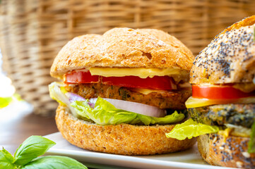 Eating of fresh and healthy vegetarian hamburgers with grilled spinach or pumpkin burgers, organic buns and vegetables