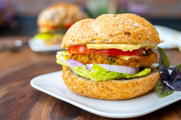 Eating of fresh and healthy vegetarian hamburgers with grilled spinach or pumpkin burgers, organic buns and vegetables