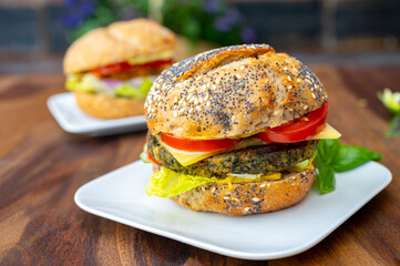Eating of fresh and healthy vegetarian hamburgers with grilled spinach or pumpkin burgers, organic buns and vegetables