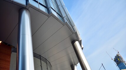 Blue curtain wall made of toned glass and steel constructions under blue sky. A fragment of a building.