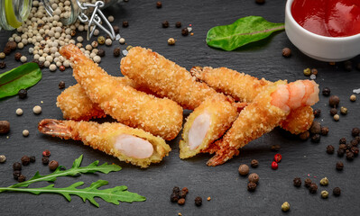 Fried Shrimps tempura with sweet chili sauce on a black stone board
