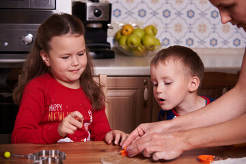 Fototapeta premium brother and sister prepare homemade cookies in the kitchen. The mood of the occasion. Fun and laughter