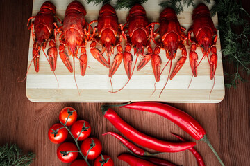 Steamed boiled crawfish on a chopping Board. Crayfish with herbs pepper and tomatoes