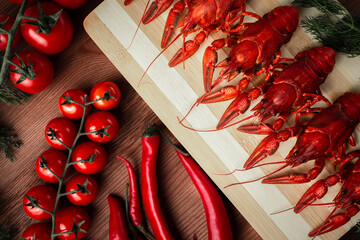 Crawfish on a chopping Board with cherry tomatoes chili peppers and herbs