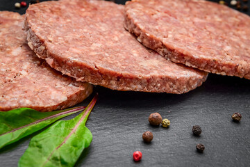 Raw Ground beef meat Burger steak cutlets on dark marble background