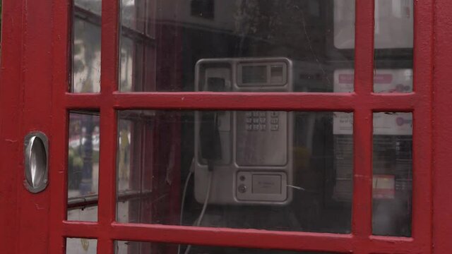 Red phone box in British city medium panning shot