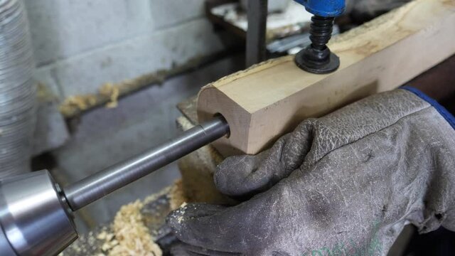 A carpenter craftsman works with the drill to drill a piece of boxwood for the construction of a bagpipe