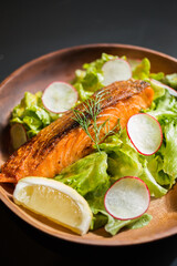 grilled norwegian salmon in wooden plate on black dining table.