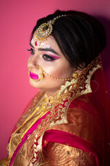 Indian bride dressed in Hindu red traditional wedding clothes sari embroidered with gold jewelry