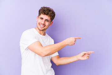 Young blond curly hair caucasian man isolated excited pointing with forefingers away.