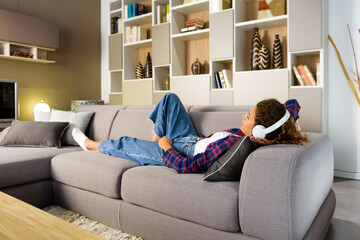 Obraz premium Young woman relaxing on a sofa listening to music