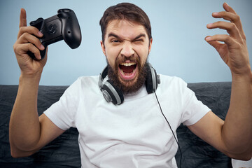 A man sits on a sofa with a gamepad in his hand. Leisure lifestyle game console