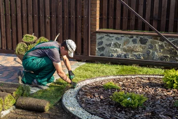 Tuinposter Landscape Gardener Laying Turf For New Lawn © Smole