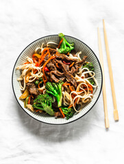 Udon noodles with beef and vegetables - delicious lunch on a light background, top view. Balanced food