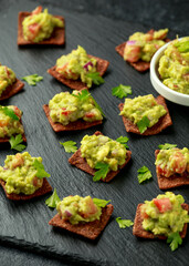 Avocado Guacamole with chipotle and poblano whole grain tortilla chips on rustic stone board