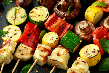 Grilled Halloumi cheese skewers with vegetables on rustic stone board