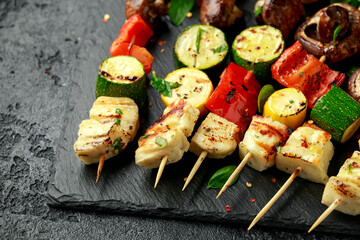 Grilled Halloumi cheese skewers with vegetables on rustic stone board