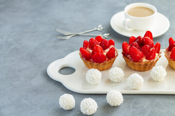 Fruit dessert tarts with cream and strawberry on stone table