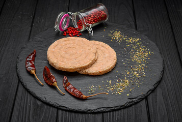 Raw burgers on paper. On black rustic background