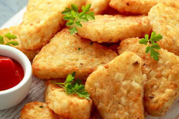 Hash brown potato with ketchup on white wooden board