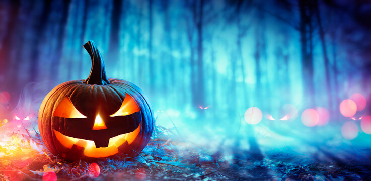 Pumpkin In Defocused Spooky Forest At Night - Halloween Concept
