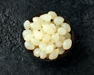 Pickled Cocktail Onions in wooden bowl on rustic black background