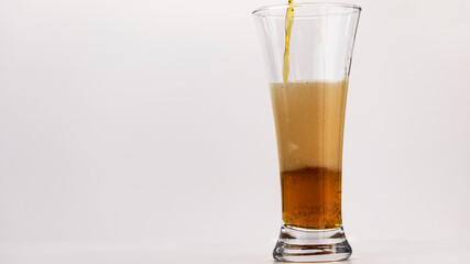 beer is poured into a glass on a white background