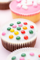 Colorful cupcakes on a pink background.