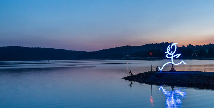 The girl is fishing on spinning. Sunset Czech Republic Lipno lake.