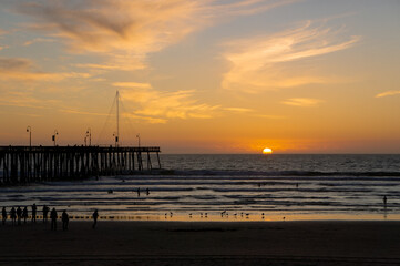 Obraz premium People Watching the Sunset Over Pismo Beach Pier, California USA