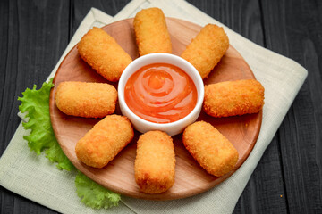 cheese nuggets with fruit sauce, on a wooden plate