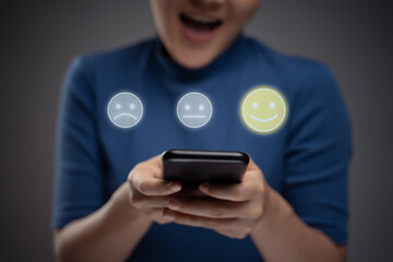 Asian woman using smart phone for voting with emoticon hologram effect.