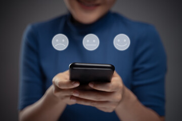 Asian woman using smart phone for voting with emoticon hologram effect.