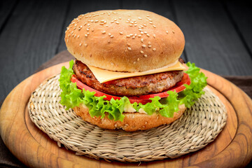 appetizing cheeseburger with tomato on wooden background