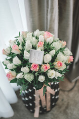 Elegant, beautiful wedding jewellery in the white box with pastel pink, yellow roses background in a big black vase Getting ready bride good morning concept.