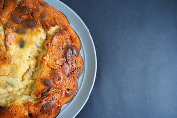 part of a round pie with pumpkin seeds from corn and rice flour on a gray plate on a black background top view . gluten-free baked goods made at home