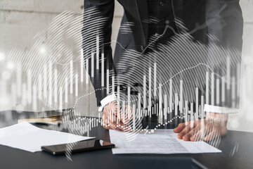 Businessman in suit signs contract. Double exposure with forex graph hologram. Man signing brokerage agreement. Financial market analysis and investment concept.