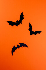 Fototapeta premium Three black paper bats on orange background