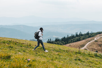 woman with backpack hiking in mountains