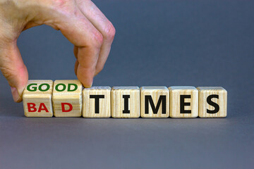 Male hand turns a cube and changes the expression 'bad times' to 'good times'. Beautiful grey background. Business concept, copy space.