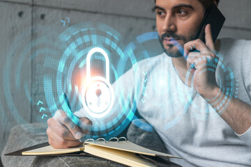 Handsome manager in casual, speaking phone and taking notes at office try to determine IT needs of customer to protect they information. Double exposure. The concept of confidentiality and privacy.