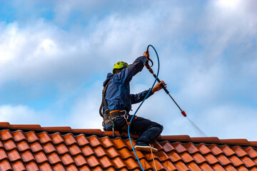 worker washing the roof with pressurized water - obrazy, fototapety, plakaty