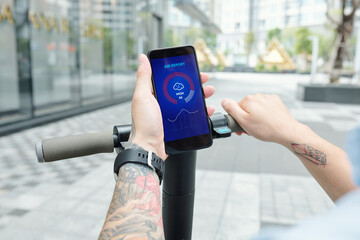 Close-up image of man checking air report via mobile applciation when riding on scooter to work
