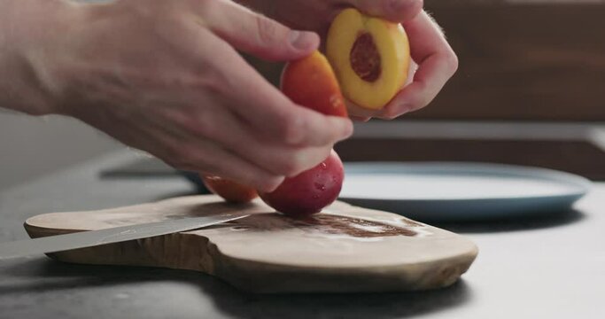 Slow motion man put nectarines halves on a olive wood board