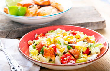 Fresh salad with grilled salmon on table.