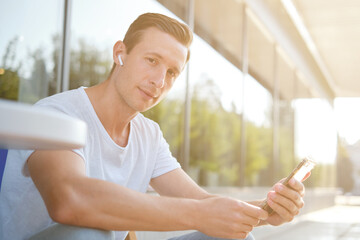 Young attractive man enjoying a cup of aromatic coffee outdoors in sunny weather