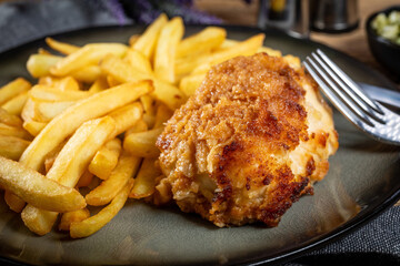 Fried chicken breast stuffed with bacon and cheese served with chips and salad.
