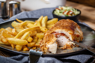 Fried chicken breast stuffed with bacon and cheese served with chips and salad.