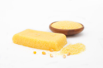 Corn polenta slice with grinded corn in a bowl on white background. Homemade palenta, healthy vegetarian food.